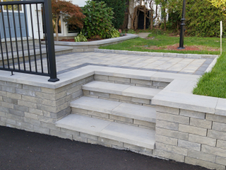 Stone staircase and interlocking paver landing creating a stunning front entrance