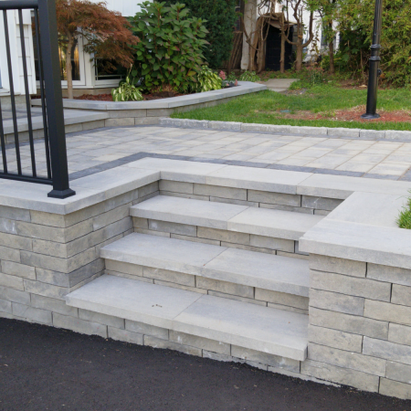 Stone staircase and interlocking paver landing creating a stunning front entrance