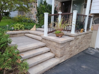 Stone staircase and interlocking paver landing creating a stunning front entrance.