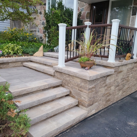 Stone staircase and interlocking paver landing creating a stunning front entrance.