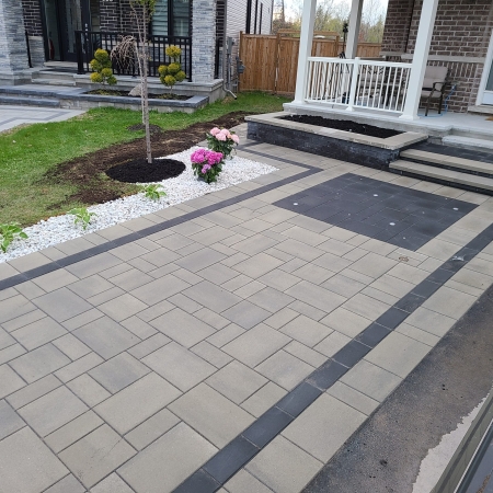 Modern front entrance with interlock driveway and walkway, featuring a sleek mix of light and dark pavers.