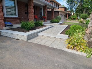 Beautifully landscaped front yard with interlock pavers, a garden bed with white stone accents, and a welcoming entryway.