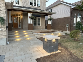 Modern front entryway with high-quality stone pavers, integrated lighting, and a welcoming porch design