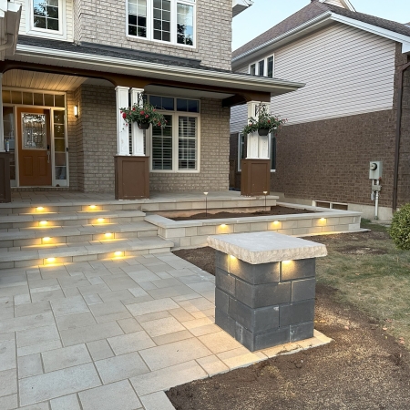 Modern front entryway with high-quality stone pavers, integrated lighting, and a welcoming porch design