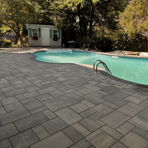 Luxurious poolside patio with modern interlock pavers and a seamless outdoor lounging area.