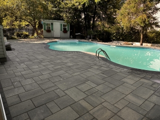 Luxurious poolside patio with modern interlock pavers and a seamless outdoor lounging area.