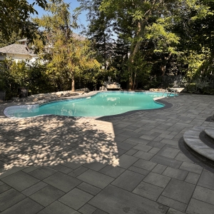 Luxurious poolside patio with modern interlock pavers and a seamless outdoor lounging area.