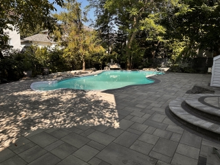 Luxurious poolside patio with modern interlock pavers and a seamless outdoor lounging area.
