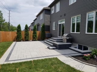 Modern backyard patio with interlock pavers, built-in steps, and seating area for outdoor living