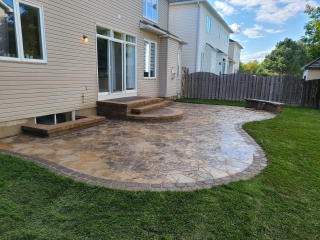 Spacious outdoor living area featuring a custom curved patio, built-in seating, and seamless transition to the lawn.