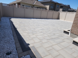 Modern backyard patio with interlock pavers, built-in steps, and seating area for outdoor living.