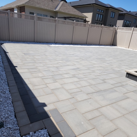 Modern backyard patio with interlock pavers, built-in steps, and seating area for outdoor living.