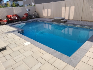 Spacious backyard pool deck featuring elegant stone pavers and a sleek border design.