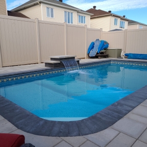 Spacious backyard pool deck featuring elegant stone pavers and a sleek border design.