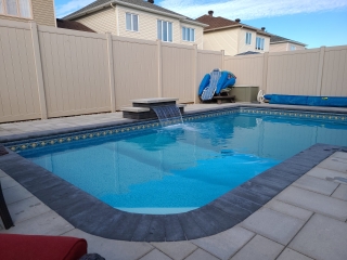 Spacious backyard pool deck featuring elegant stone pavers and a sleek border design.